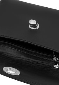 Cartera de cuero negro con un cierre de presión plateado, cierre de cremallera y detalles texturizados. Diseño compacto para un fácil almacenamiento y accesibilidad.