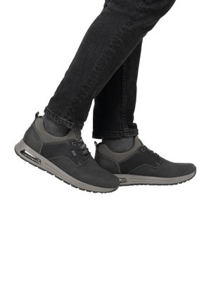 Gray athletic shoes with a smooth finish, lace-up design, air sole, and contrasting dark gray accents. Worn with dark jeans.
