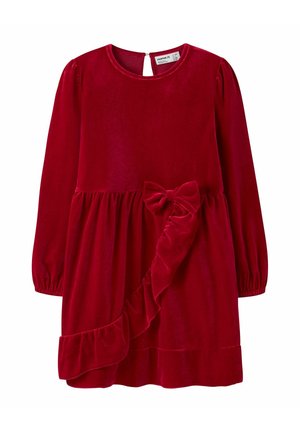 Robe en velours rouge à manches longues, décolleté rond et fermeture en forme de clé au dos. Elle présente un ourlet volanté et un accent en forme de nœud à la taille.