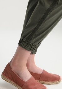 Olivgröna stretchbyxor med ett texturerat sidopanel, ihop med rosa mockaespadrillos med jutesula.