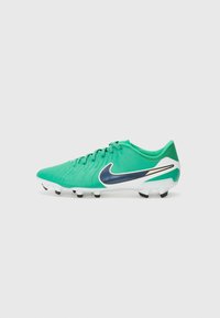 Green synthetic soccer cleat with textured upper, white sole, black studs, and a blue Nike swoosh accent. Laced design for secure fit.