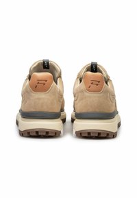 Para beżowych zamszowych sneakerów z brązowymi gumowymi podeszwami, beżowymi skórzanymi łatkami na pięcie z wytłoczonym stylizowanym logo "F" oraz czarnymi pętlami do zakupu.