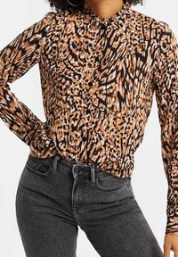 Topp med leopardtryck i nyanser av brunt, svart och kräm; har en krage, knappstängning fram och långa ärmar; strukturerat tyg.