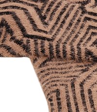 Țesătură de culoare bej cu un model în zigzag negru, având o suprafață moale și texturată, cu un aspect ușor pufos. Marginile sunt finisate uniform.