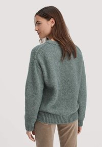 Übergroßer gestrickter Pullover aus weichem, strukturiertem Teal-Stoff mit geripptem Saum und Bündchen, Rundhalsausschnitt und überschnittenen Schultern.