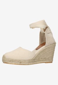 Beige canvas espadrille wedge schoen met geweven jute wikkeling en enkelbandje. Zachte textuur, ronde neus en patroon op de achterkant.