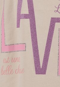 Un tissu beige avec de grandes lettres roses brillantes "L" et "V", accentuées de strass et de texte imprimé dans une police rose douce.