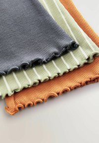 Quatre pièces de tissu côtelé en gris, à rayures vertes et orange, présentant un bord festonné. Chaque tissu a une surface texturée.