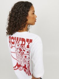Camiseta de algodón blanca con un gran diseño gráfico en rojo de un sombrero de cowboy y un lazo, con el texto "HOWDY". Mangas cortas, corte casual.