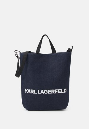 Granatowa materiałowa torba na ramię z czarnymi rączkami i paskiem na ramię, z białym napisem "KARL LAGERFELD" z przodu.