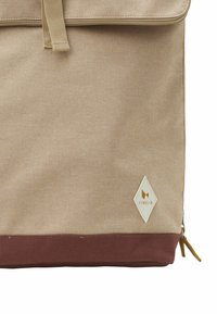 Beige stofrygsæk med en bordeaux bund. Har en topklap og et logo i diamantform. Inkluderer en sidelomme med lynlås og struktureret overflade.