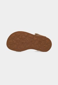 Κάτω μέρος καφέ σανδαλιού με ανάγλυφα σχέδια κοχυλιών και γράμματα που σχηματίζουν τη λέξη «POMDAP».