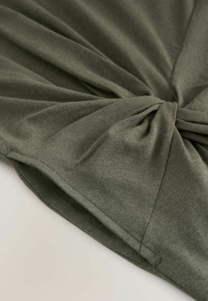 Olivově zelený bavlněný top s otočeným předním designem, hladkou texturou a splývavým materiálem s jemnými švy.