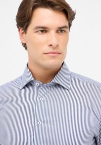 Camicia da uomo a righe blu e bianche, con colletto button-down, piccoli bottoni bianchi e un design aderente con linee verticali.