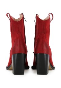 Bottes de cheville en suède rouge avec un talon bloc haut, dotées d'une fermeture éclair et d'une languette à l'arrière. Texture lisse, design épuré.