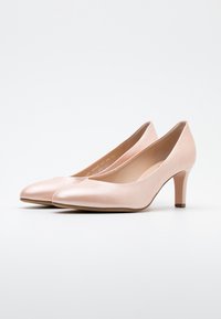 Zapatos de tacón alto de cuero rosa con punta afilada y un tacón de bloque de 7 cm. Textura suave con un sutil patrón de grano. Diseño minimalista, sin adornos.