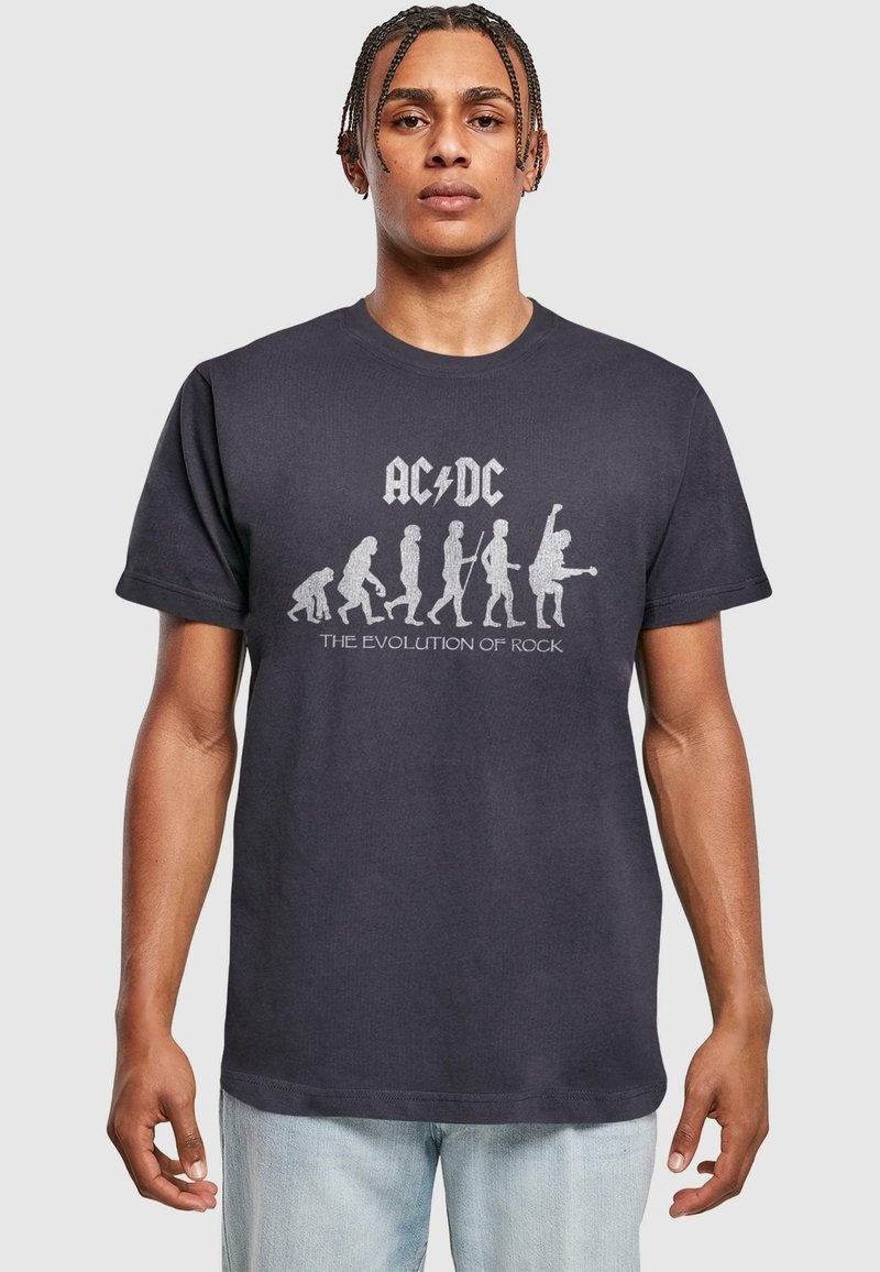 Fekete pamut póló, amelyen az "AC/DC" logó látható, valamint a rock zene fejlődését ábrázoló fehér grafikával.