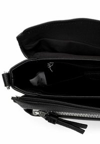 Borsa clutch in pelle nera con finitura texturizzata, chiusura con cerniera e fodera in tessuto. Presenta una piccola tasca interna con un'etichetta visibile.