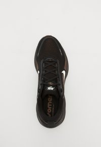 Chaussure de course Nike noire avec logo swoosh blanc, lacets noirs et semelle amortissante vue de dessus sur fond uni.