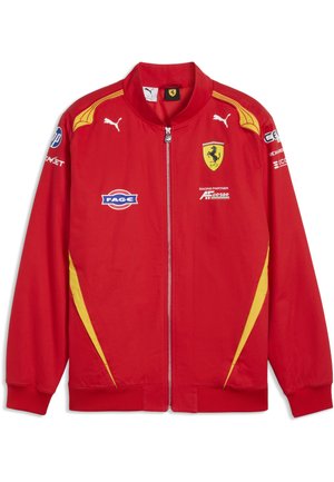 Rød lynlåstrøje med gule accenter, Ferrari- og Puma-logoer samt flere sponsor-patches foran og på ærmerne.