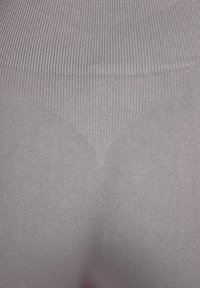 Lichtgrijze legging met geribbelde textuur, voorzien van een hoge taille en een glad, nauwsluitend ontwerp. De stof lijkt rekbaar en zacht te zijn.