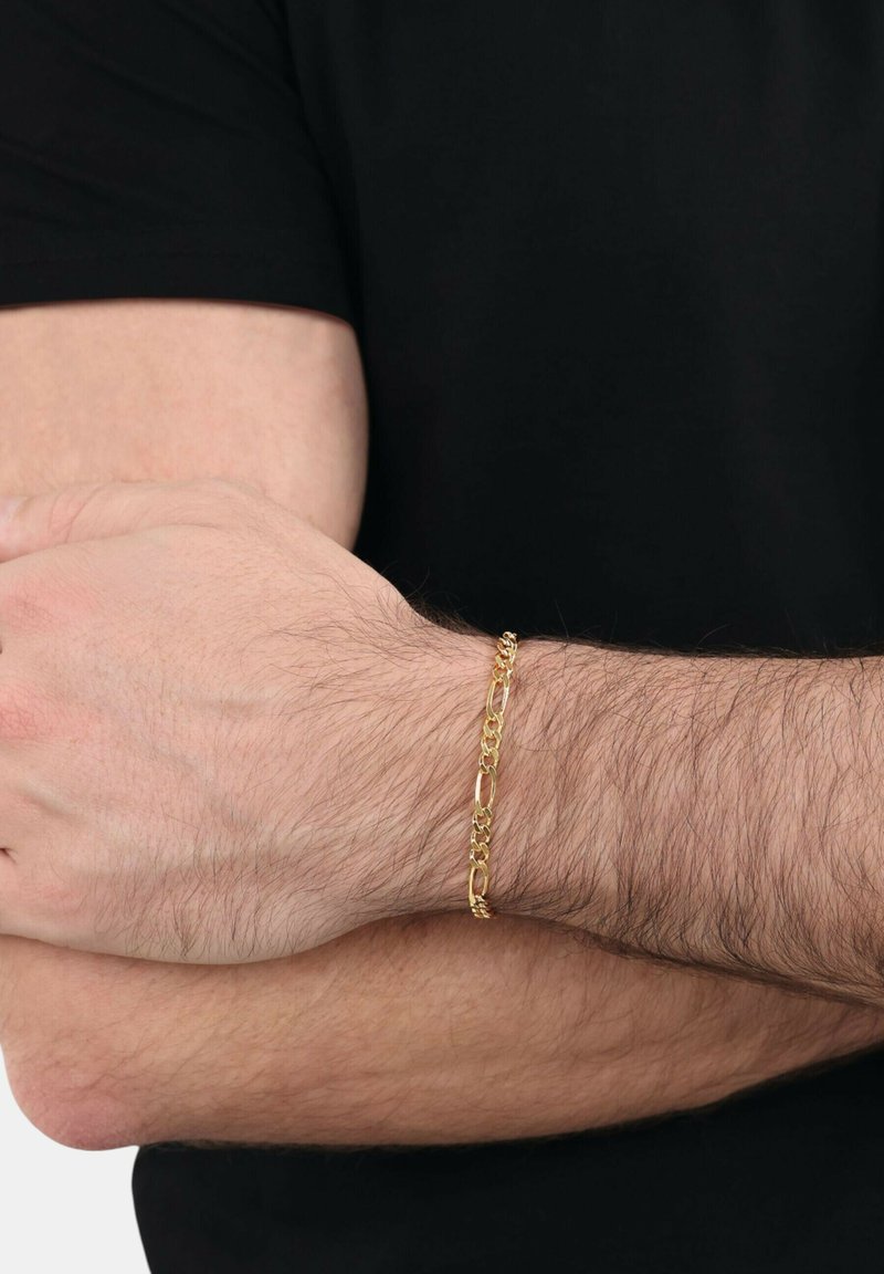 Bracciale in oro a catena con forme ovali e rotonde collegate, indossato su un polso. Finitura testurizzata e dettagli della chiusura visibili nei punti di connessione.