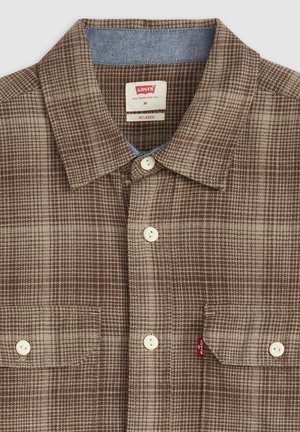 Camicia a quadri marrone e beige con bottoni, colletto, due tasche frontali, bottoni bianchi e una etichetta del marchio Levi's all'interno del colletto.