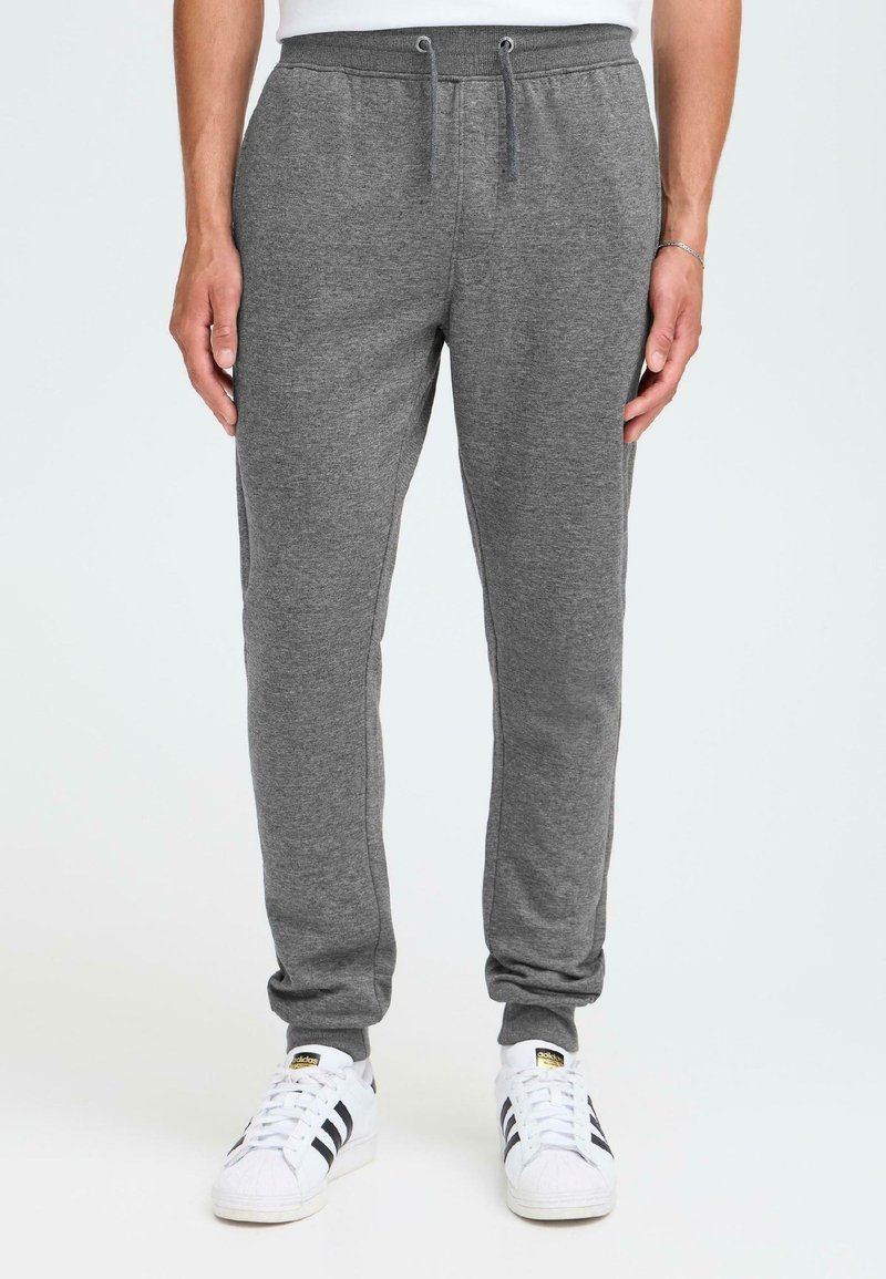 Grå joggebukser laget av mykt stoff, med elastisk liv med snor, smale ben og ankelmansjetter, kombinert med hvite joggesko.