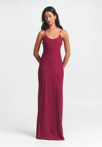 Mauvini bešvarkiai ilgi suknelė su plonomis petnešomis; prigludusi siluetas; glotni, matinė medžiaga; iki kulkšnies ilgio dizainas.