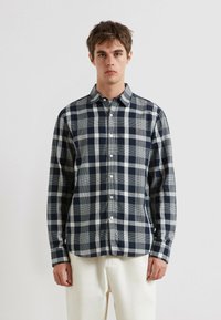 Karierte Button-Up-Hemd in Marineblau, Grau und Weiß. Baumwollstoff, normale Passform, lange Ärmel, mit einem kleinen Logo nahe der Brust.