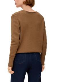 Pull en laine marron avec une finition texturée, col rond et poignets côtelés, associé à un pantalon en jean. Vue de dos.