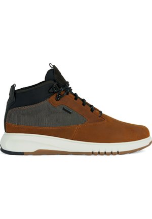 Zapato alto de cuero marrón con acentos de malla negra, entresuela blanca y suela de goma texturizada. Presenta cordones negros y tobillo acolchado.