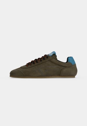 Vue de profil d’une basket en daim brun olive, avec des lacets noirs et orange, des détails bleus au talon et sur la languette, et une semelle marron.