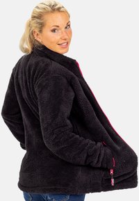 Schwarze Fleecejacke mit hohem Kragen, Reißverschluss vorne und pinken Akzenten. Sie hat eine weiche Textur und seitliche Taschen.