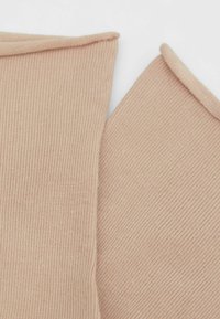 Beige ribbet stof med en blød tekstur. To overlappinge stykker med afrundede kanter og et ensartet mønster overfladen.