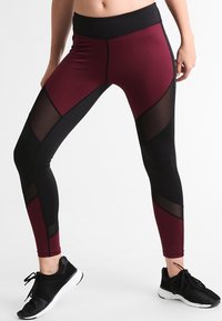 High-waisted leggings in burgundy and black, featuring mesh panels, a smooth texture, and a form-fitting design, suitable for athletic wear.