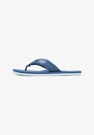 Blue flip-flop sandal with a textured fabric strap, white stitched detail, and a crest logo patch on the side strap.