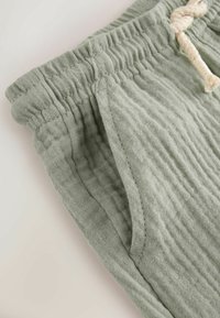 Lichtgroene, gestructureerde linnen short met een elastische tailleband en trekkoord, voorzien van zijzakken en een zachte, gekreukte afwerking.