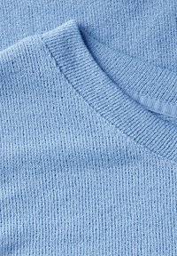 Helles blaues Strickpullover mit gerippter Struktur und klassischem Rundhalsausschnitt, der an den Kanten glatt und fein verarbeitet ist.