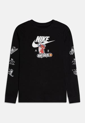 T-shirt noir à manches longues Nike avec logo blanc, un personnage basket rouge sur un skateboard, texte "Just do it" et illustrations blanches de sports d'hiver sur les manches.