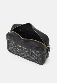 Borsa a tracolla nera in pelle con un motivo logo testurizzato in nero e grigio, hardware dorato e chiusura con zip con tasche interne.