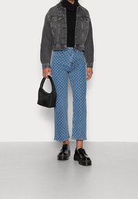 Chaqueta de denim negra, suéter negro ajustado, vaqueros azul a cuadros, bolso negro y zapatos negros brillantes con suelas gruesas.
