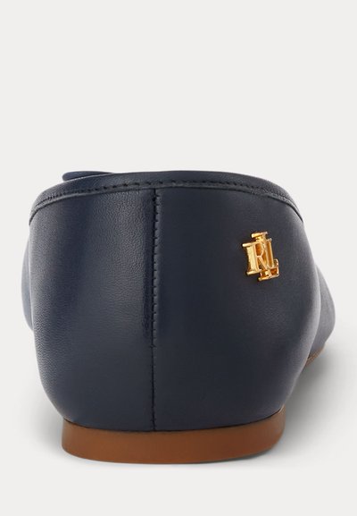 Chaussure plate en cuir bleu marine montrant une vue arrière avec une couture verticale et un petit logo doré "RL" sur le côté près du talon.