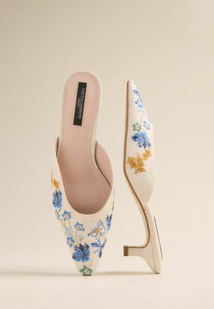 Pointed-toe mules crafted from off-white fabric, featuring blue and yellow floral embroidery, with a small, clear heel and open back design.