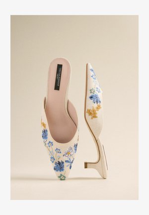 Puntige muiltjes gemaakt van lichtbeige stof, voorzien van blauwe en gele bloemenborduursels, met een kleine, transparante hak en een open achterkant.