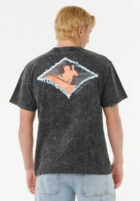 Camiseta de algodón negra con un acabado texturizado y desgastado. La parte trasera presenta un gráfico colorido de dos figuras en forma de diamante contorneadas en azul.