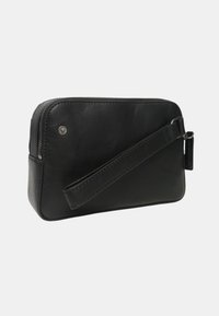 Pochette da polso rettangolare nera in pelle con chiusura a zip e tracolla attaccata su sfondo chiaro.