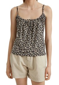 Haut caraco fleuri à fines bretelles ; présente un décolleté froncé, un fond sombre, et des fleurs blanches et roses. Associé à un short beige.