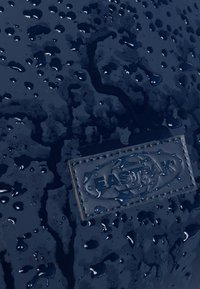 Navy wodoodporny materiał z kropelkami wody, z teksturowaną powierzchnią i naszywaną prostokątną metką z logo "EASTPAK".