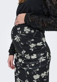 Μαύρη φλοράλ φούστα με λευκά σχέδια, με ζωνάκια στα πλαινά για ελαστικότητα, σετ με μαύρο τοπ που διαθέτει υφασμένα μανίκια και παγιέτες.